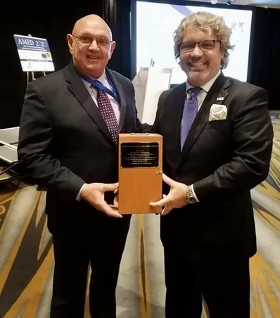 Dr. Linger receiving recognition at an Academy of Microscope Enhanced Dentistry ceremony