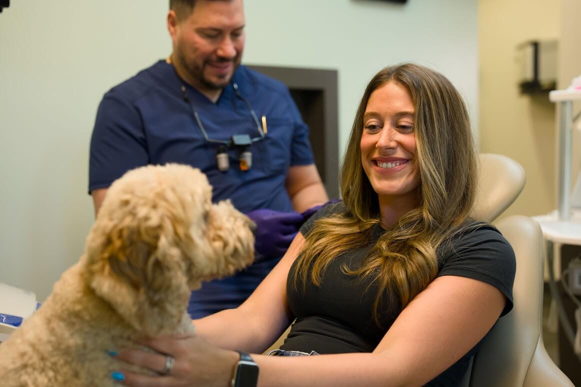 Tedi, the Barrero Dental Boutique support dog, greeting a smiling patient during a visit