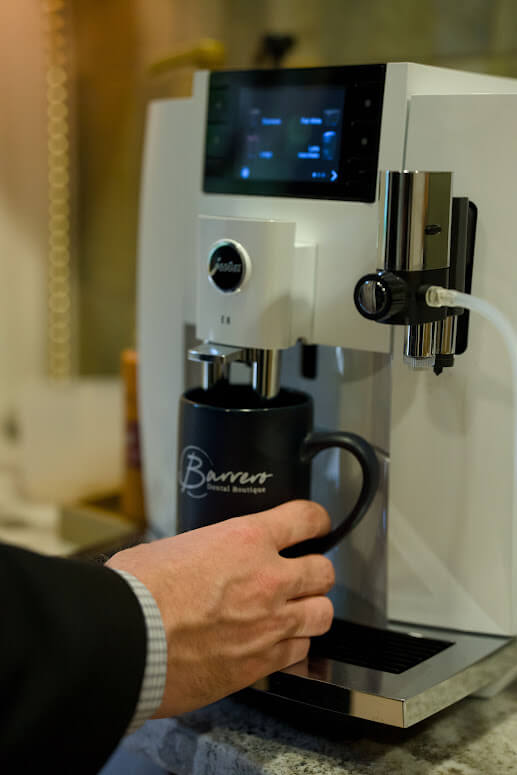 A patient preparing coffee in the Barrero Dental Boutique waiting room
